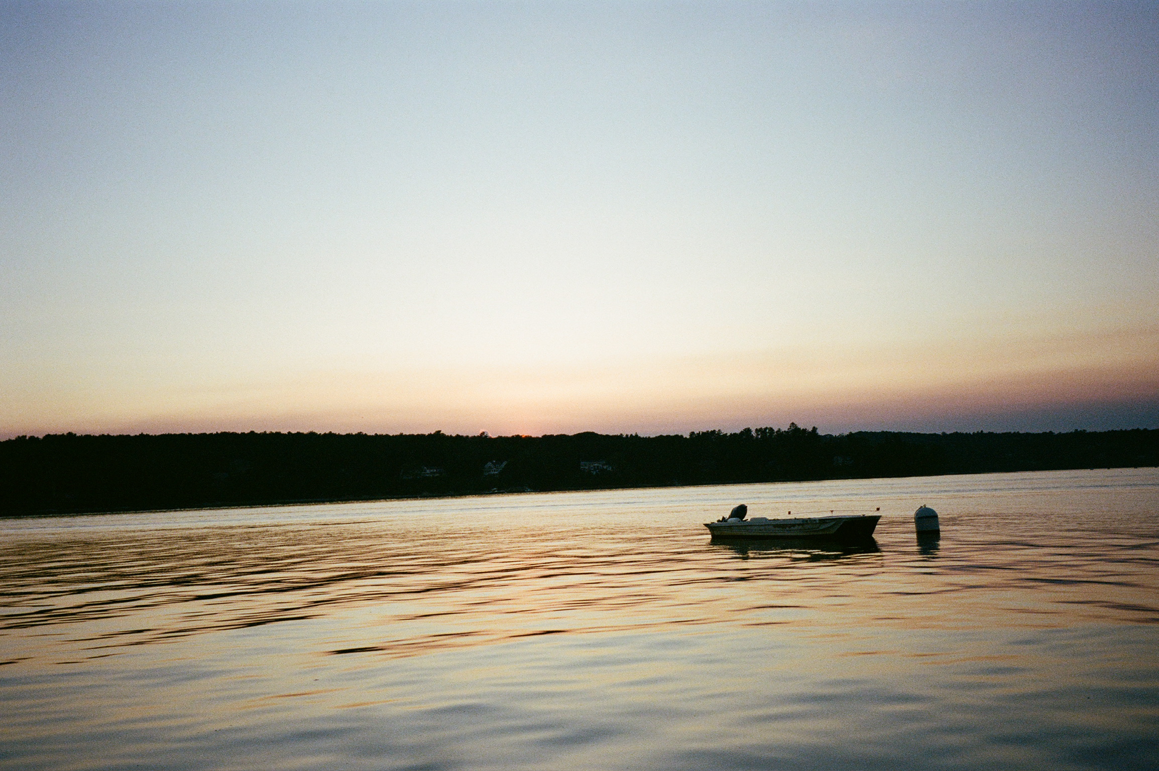 Boat on calm water at sunset on Casco Bay